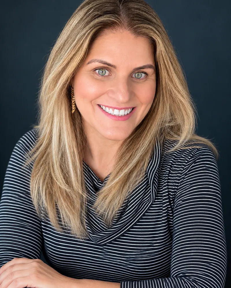 Retrato de Ana Junqueira sorrindo, de blusa listrada